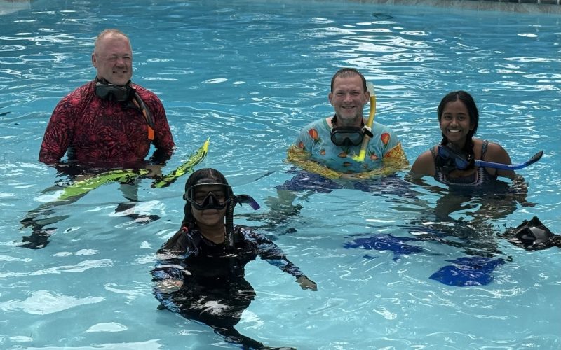 Group of scuba students and instructors smiling in the pool after completing confined water scuba training
