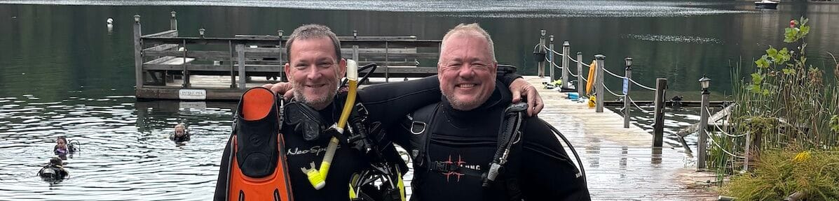 Two scuba divers smiling in gear at Lake Phoenix after certification.