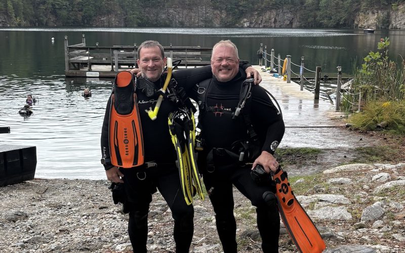 Two scuba divers smiling in gear at Lake Phoenix after certification.