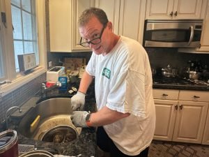 DWF shucking oysters in a kitchen, looking up from the sink.