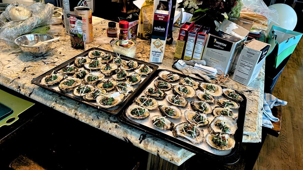 Kitchen counter covered with oyster trays, salt, and ingredients.