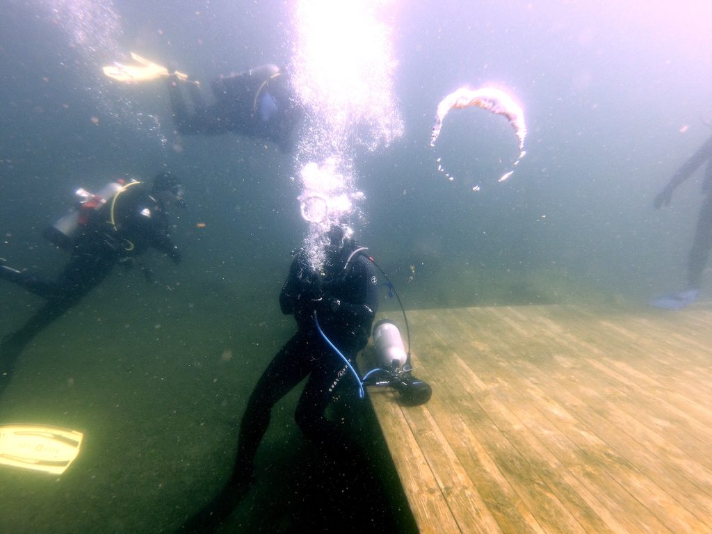 Diver firing bursts of air bubbles underwater from a Torrid Pulse bubble gun, defending against approaching “zombies.”
