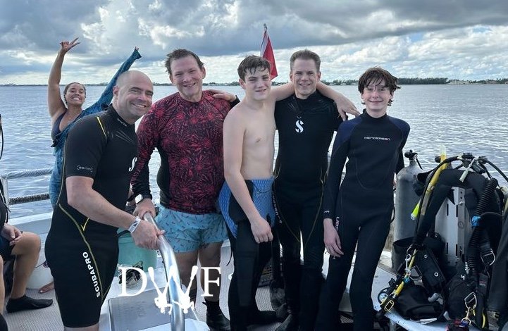 Four divers (and DWF) smiling on deck after dives