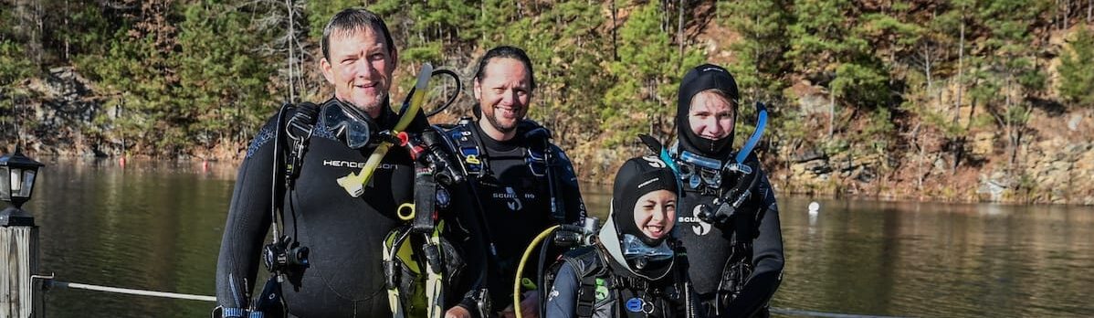 Four divers standing on a dock at Lake Phoenix on a sunny fall day