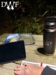 Logbook, DWF mug, and gear on a table at night