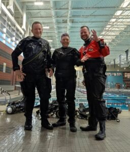 Dry suit divers standing together in full gear during winter certification dives