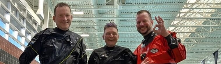 Dry suit divers standing together in full gear during winter certification dives