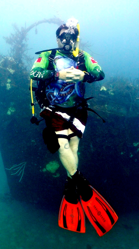 Relaxed scuba diver hovering comfortably underwater with crossed legs and calm posture.